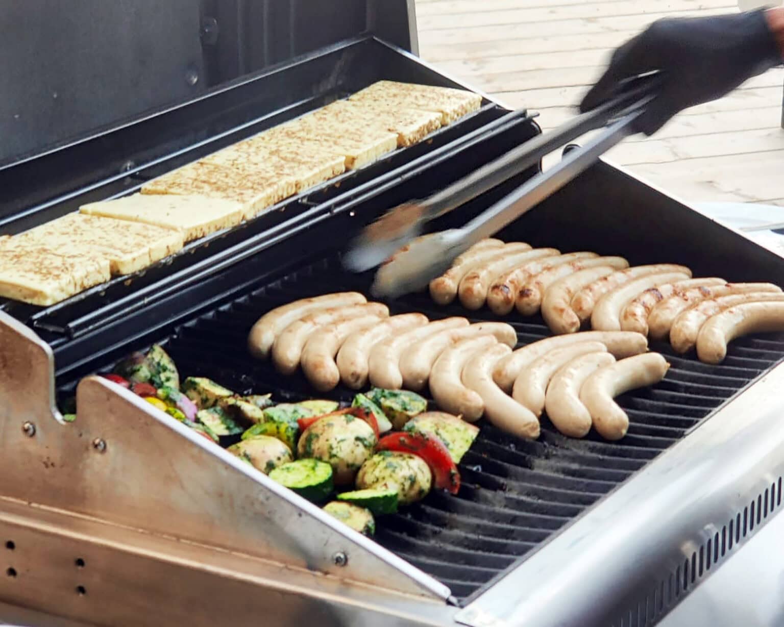 Würstchen, Gemüsespieße und Käse auf einem Grill